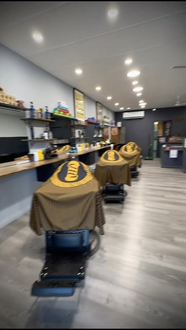 Inside Barberz Den barbershop in Kiara — row of barber chairs with signature gold-crest capes